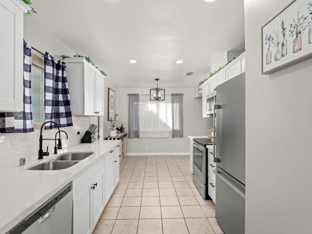 kitchen featuring white cabinets, appliances with stainless steel finishes, decorative backsplash, and a sink