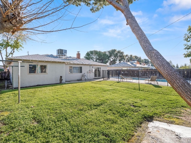 back of house with a chimney, central air condition unit, stucco siding, a lawn, and fence