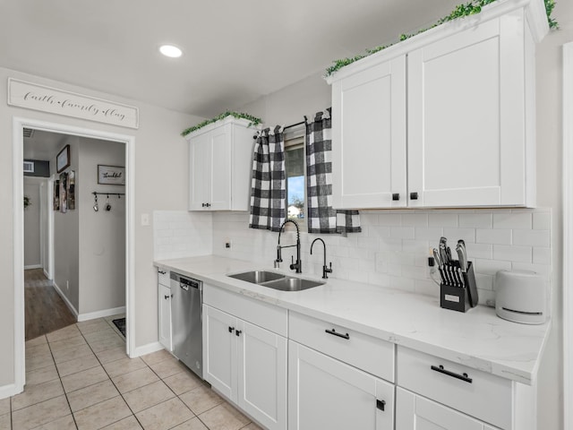 kitchen featuring a sink, white cabinets, stainless steel dishwasher, light stone countertops, and tasteful backsplash