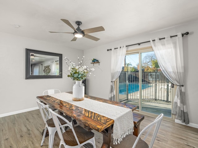 dining room featuring a ceiling fan, light wood-style flooring, and baseboards