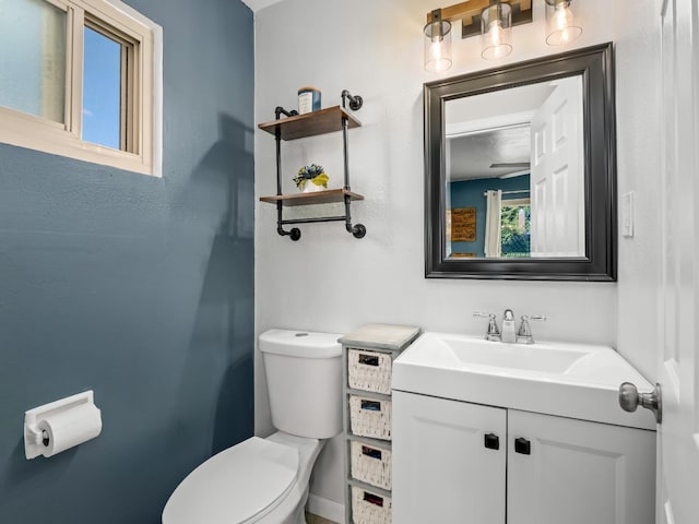 half bath featuring plenty of natural light, vanity, and toilet