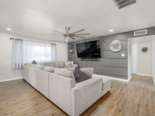 living room featuring a ceiling fan, visible vents, and wood finished floors