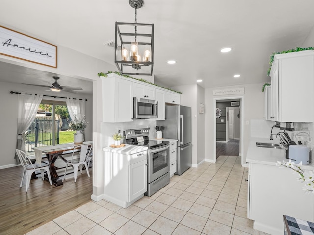 kitchen with white cabinets, stainless steel appliances, a sink, and light countertops