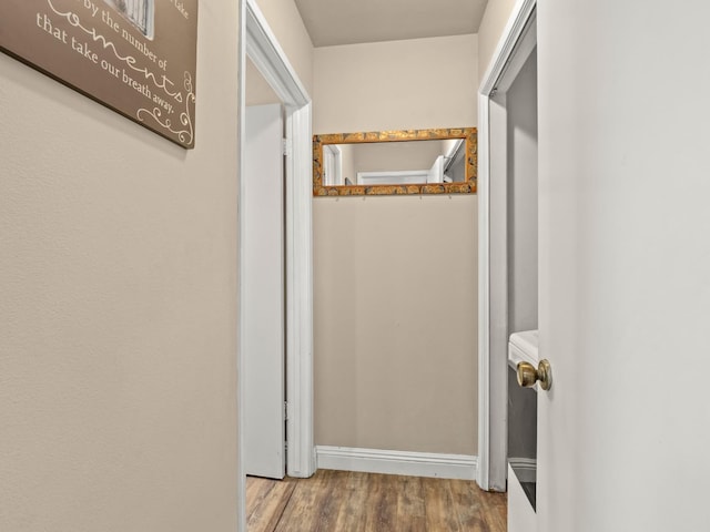 hall with baseboards and wood finished floors