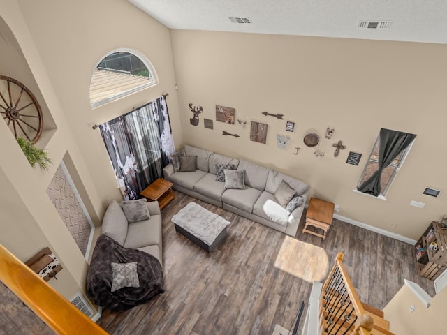 living room featuring high vaulted ceiling, visible vents, a textured ceiling, and wood finished floors