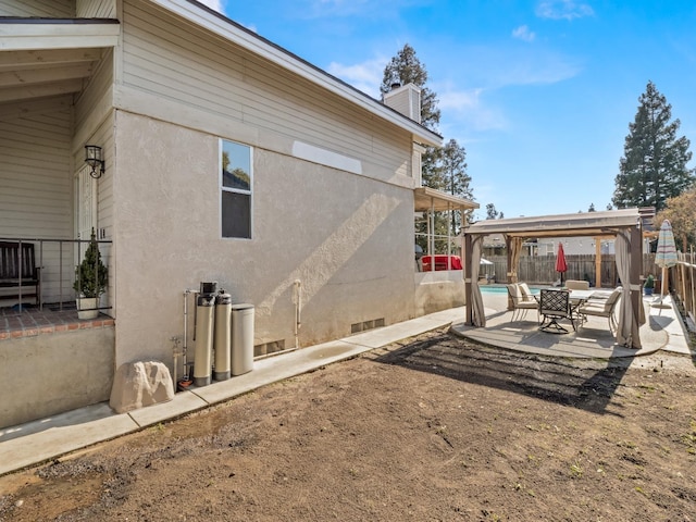 rear view of house featuring a patio, fence, and stucco siding