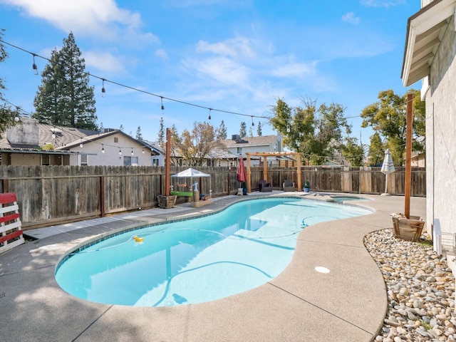 view of pool with a fenced backyard, a pool with connected hot tub, and a patio