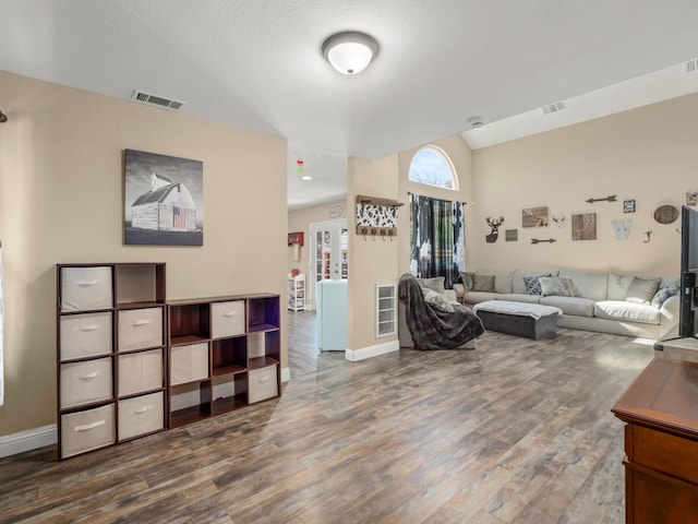 living room featuring visible vents, vaulted ceiling, and wood finished floors