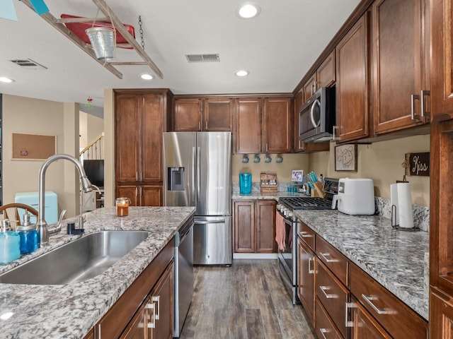 kitchen featuring stainless steel appliances, visible vents, a sink, and dark wood-style floors