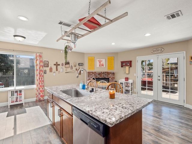 kitchen featuring dark wood-style flooring, a sink, visible vents, a brick fireplace, and dishwasher