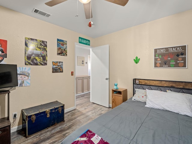 bedroom with ceiling fan, wood finished floors, visible vents, and baseboards