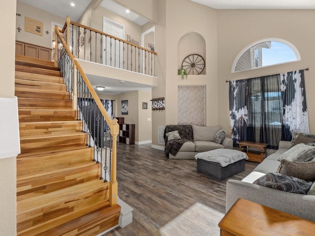 living area with visible vents, a high ceiling, wood finished floors, baseboards, and stairs