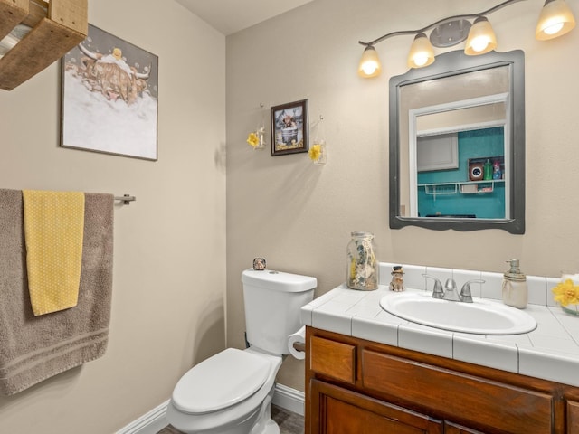 bathroom with toilet, baseboards, and vanity