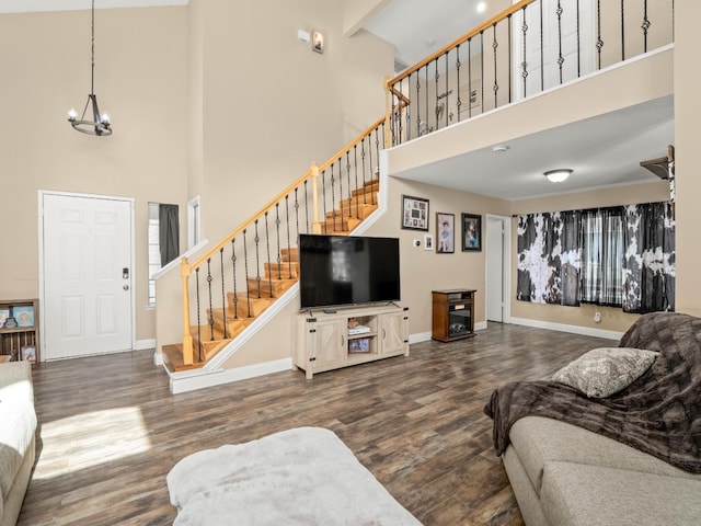 living area with baseboards, stairway, a chandelier, and wood finished floors