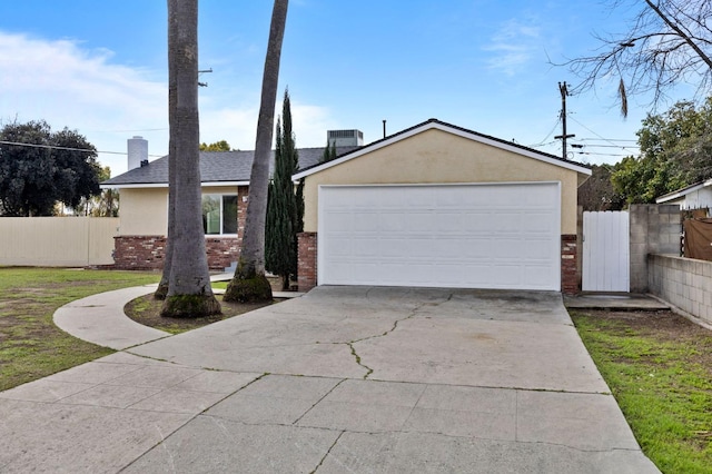 view of front facade featuring brick siding, fence, a detached garage, and stucco siding