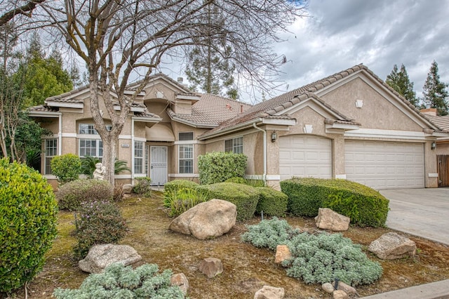 view of front facade featuring a garage, concrete driveway, a tile roof, and stucco siding