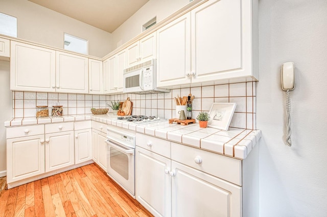 kitchen with white appliances, tile counters, and decorative backsplash