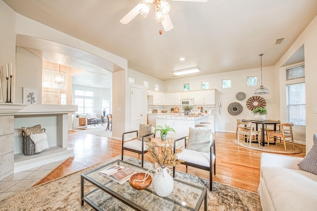 living room featuring visible vents, ceiling fan, light wood-style flooring, and baseboards