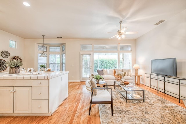 living area featuring ceiling fan, baseboards, visible vents, and light wood-style floors