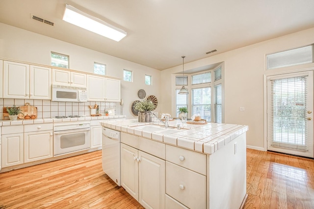 kitchen featuring white appliances, visible vents, a sink, and tile countertops