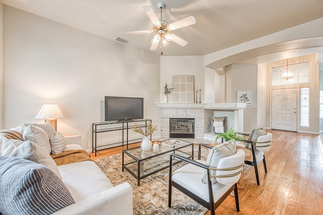 living room with baseboards, a tiled fireplace, visible vents, and light wood-style floors