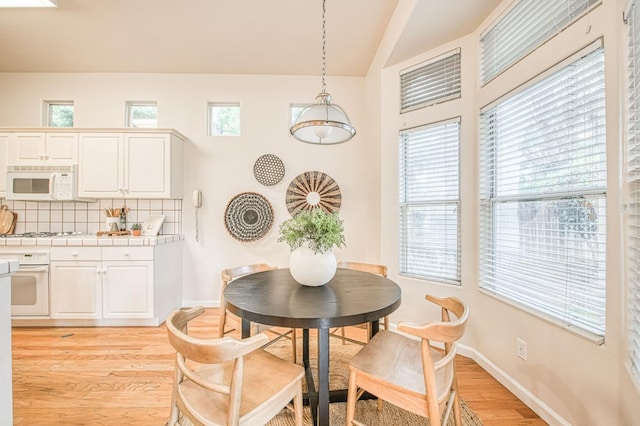 dining room featuring light wood-type flooring, baseboards, and a wealth of natural light