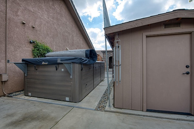 view of property exterior with stucco siding, a hot tub, and an outdoor structure