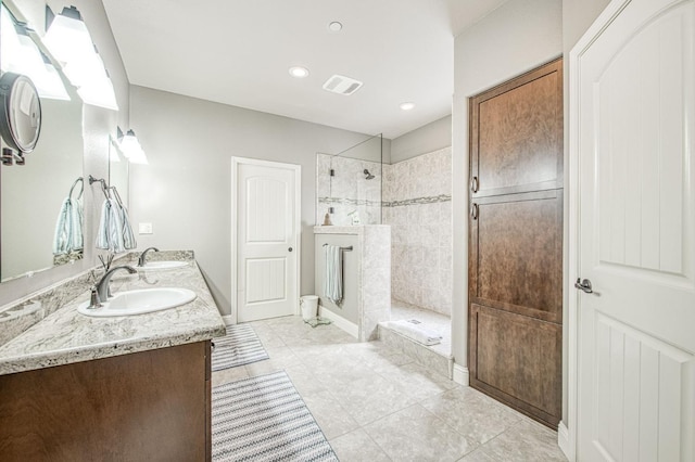 full bath with double vanity, walk in shower, a sink, and visible vents