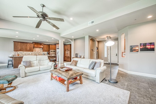 living area with arched walkways, baseboards, visible vents, and recessed lighting