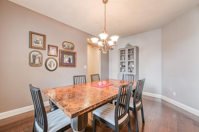 dining area featuring a notable chandelier, dark wood finished floors, and baseboards