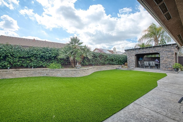 view of yard featuring an outdoor stone fireplace and a patio area