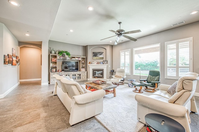 living area with arched walkways, recessed lighting, visible vents, a glass covered fireplace, and baseboards