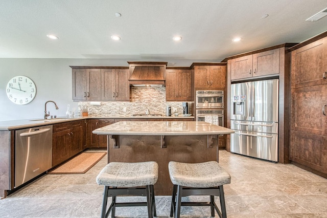 kitchen featuring a center island, custom exhaust hood, visible vents, appliances with stainless steel finishes, and a sink