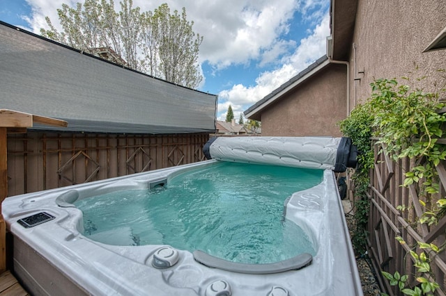 view of pool with a hot tub and fence