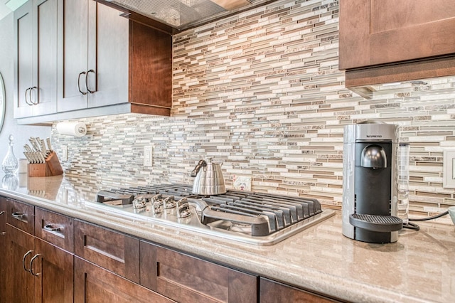 kitchen featuring stainless steel gas stovetop, decorative backsplash, and light countertops