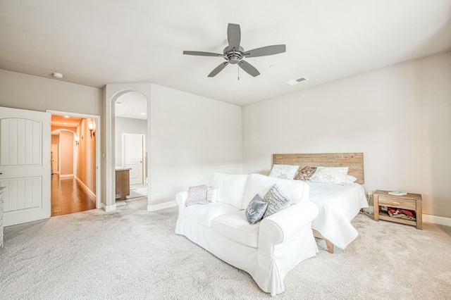 bedroom with carpet floors, arched walkways, visible vents, and baseboards