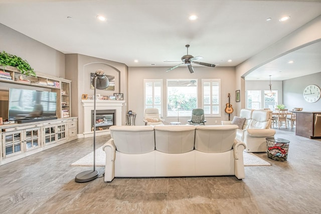 living room with recessed lighting, arched walkways, ceiling fan, and a glass covered fireplace