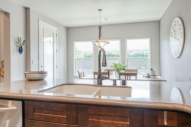 kitchen featuring stainless steel dishwasher, a sink, visible vents, and decorative light fixtures