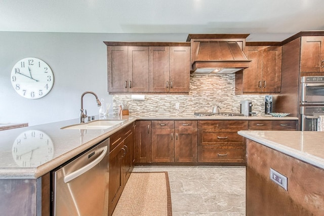 kitchen with tasteful backsplash, appliances with stainless steel finishes, a sink, and custom range hood