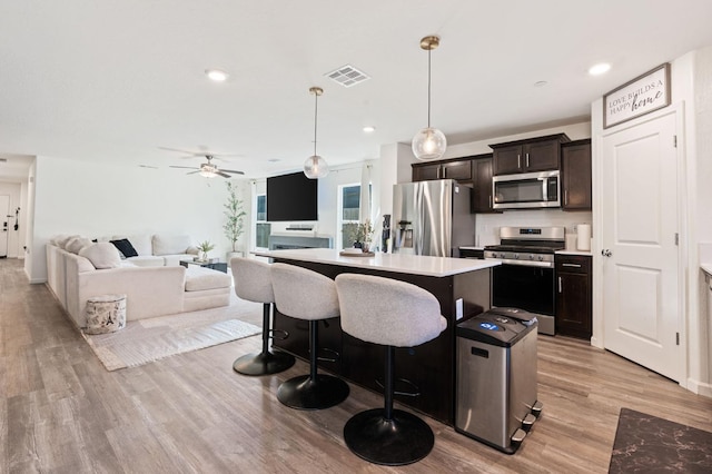 kitchen featuring a breakfast bar area, light wood-style flooring, stainless steel appliances, visible vents, and a center island