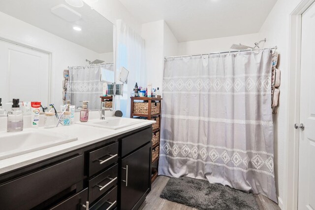 bathroom featuring a shower with curtain, double vanity, a sink, and wood finished floors