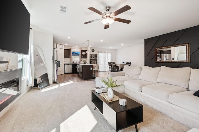 living room featuring light wood finished floors, ceiling fan, visible vents, and recessed lighting