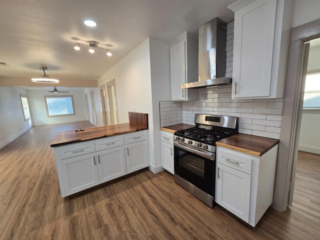 kitchen featuring stainless steel gas stove, butcher block counters, dark wood-style flooring, and wall chimney range hood