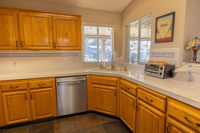 kitchen with dishwasher, brown cabinetry, a sink, and backsplash