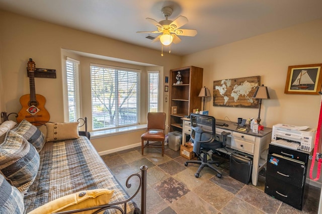 home office featuring stone finish flooring, visible vents, ceiling fan, and baseboards