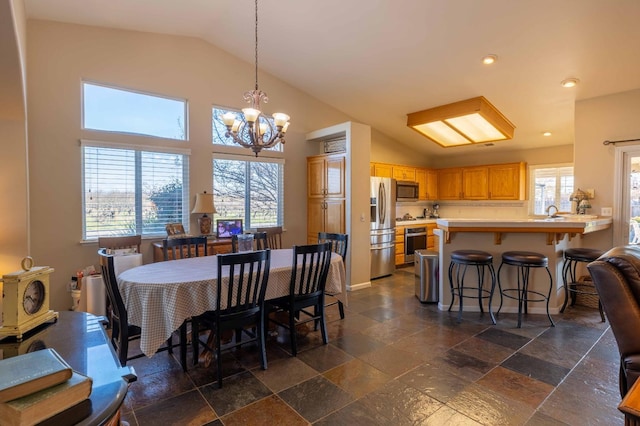 dining space featuring high vaulted ceiling, stone tile floors, recessed lighting, a notable chandelier, and baseboards