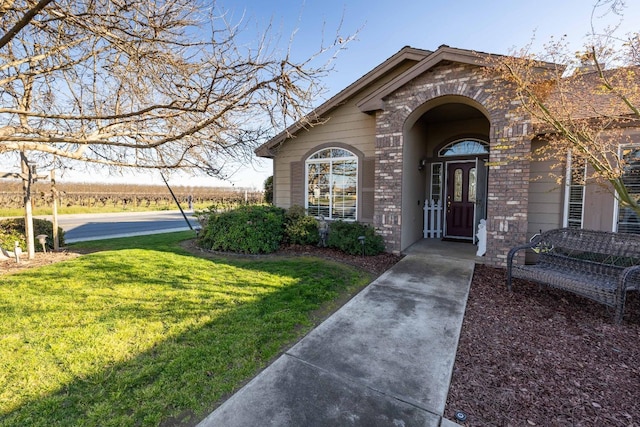 property entrance featuring brick siding and a yard