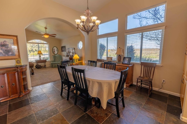 dining area featuring arched walkways, baseboards, plenty of natural light, and stone tile floors