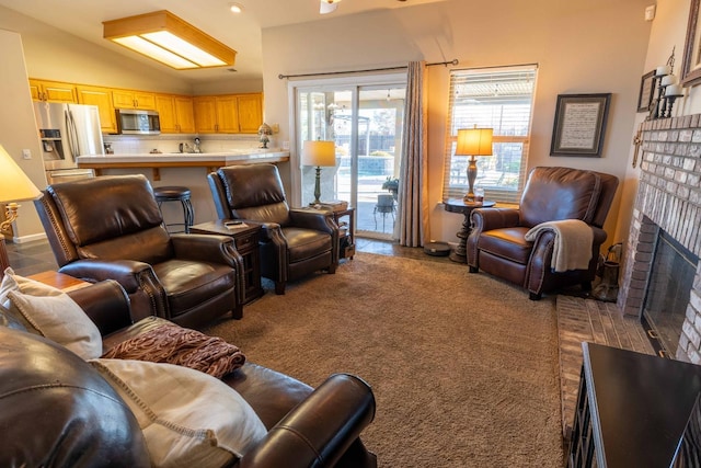 living area featuring a brick fireplace, vaulted ceiling, and carpet flooring