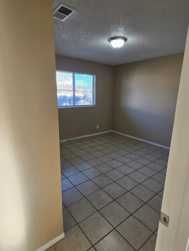 spare room with a textured ceiling, visible vents, and baseboards